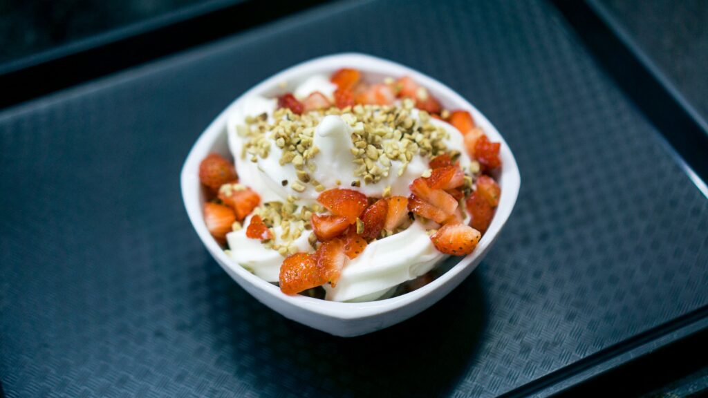 A bowl of yogurt with strawberries and granola, ideal for a nutritious snack after swimming to boost recovery