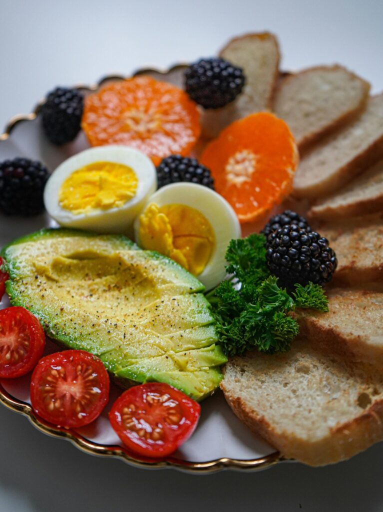 A nutritious breakfast plate with avocado, eggs, tomatoes, and bread, providing energy and protein for swimmers